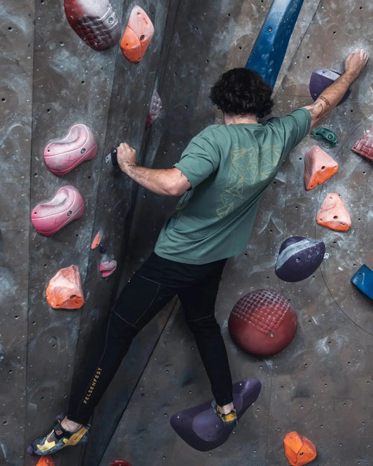 Boulderer in der langen Felsenfest Boulderhose Obsidian mit beigen Nähten an der Boulderwand